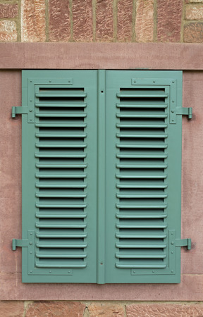 Closed green window shutter, house wall made of sandstoneの写真素材