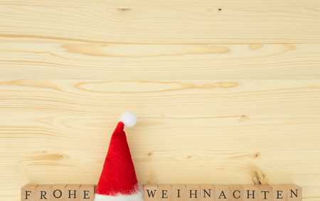 Christmas hat and the german words for Merry Christmas (Frohe Weihnachten) on wood, spruce, firの写真素材