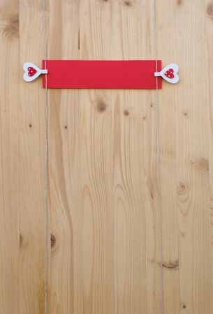 Two hearts with clothes pegs and red paper on a cord on woodの写真素材