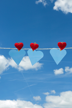 Three hearts with clothes pegs and three hearts of paper on a cordの写真素材