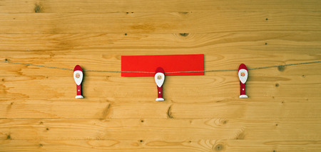 Three christmas men with clothes pegs on a cord on wood