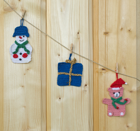 Several crocheted christmas hangers on a cord on wood, backgroundの写真素材
