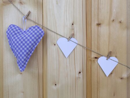 Three hearts with clothes pegs on a cord on woodの写真素材