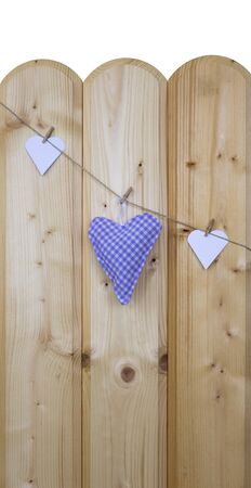 Three hearts with clothes pegs on a cord on woodの写真素材