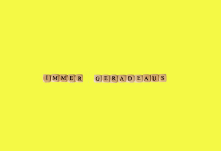 The german words for always straight ahead, isolated on yellowの写真素材