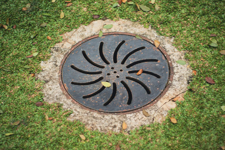 Manhole cover on the green grass in the garden, vintage style