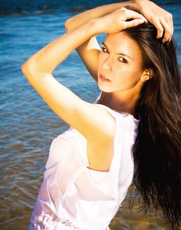 Beautiful sensual brunette girl standing in blue waterの写真素材