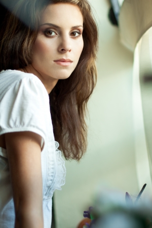 Beautiful young woman standing by a windowの写真素材