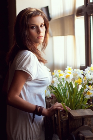 Beautiful young woman standing by a windowの写真素材