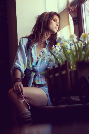 Beautiful young woman looking through a windowの写真素材