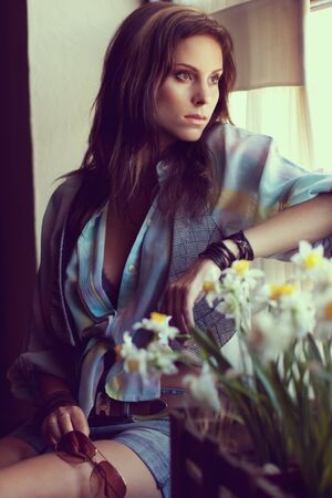Beautiful young woman looking through a windowの写真素材