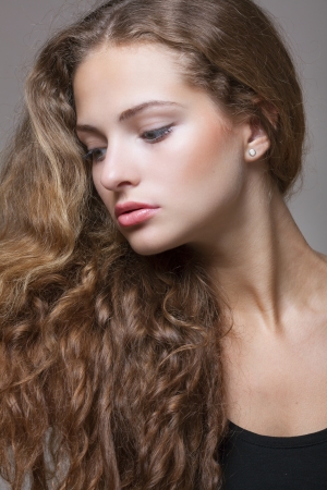 Closeup portrait of a beautiful young brunette woman with natural makeup, perfect skin and gorgeous curly hairの写真素材