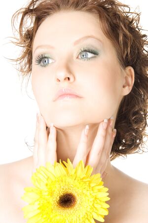 Closeup studio portrait of a beautiful young woman with yellow flower, isolated on white backgroundの写真素材