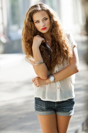 Closeup portrait of a beautiful young brunette woman with natural makeup, perfect skin and gorgeous curly hair outdoorsの写真素材