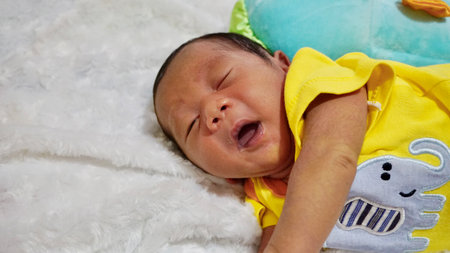 newborn baby boy, wearing yellow clothes, sleeping on a soft mattressの写真素材