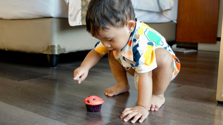 asian baby boy and cupcake on the floor, funny behavior of children