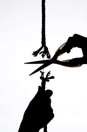 A hand holds a rope, scissors cuts the same string