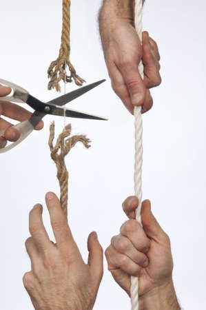 A hand holds a rope, scissors cuts the same stringの写真素材