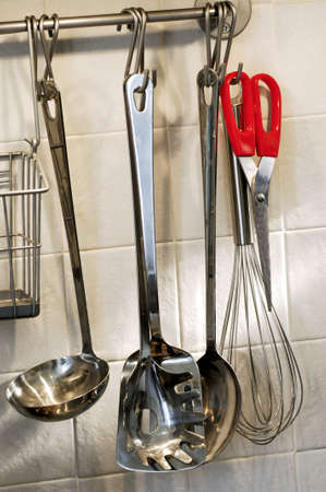 Cooking utensils hanging on the wall in a kitchenの写真素材