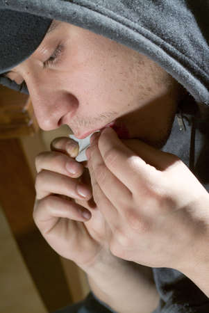Boy prepares and smokes a joint in an interiorの写真素材
