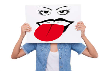 Girl holds a sign in front of her face on which is drawn a face sticking out her tongueの写真素材