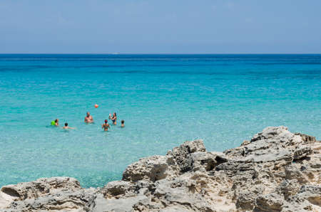 Formentera, Spain - July 22, 2015: Numerous family plays with the ball in a transparent blue and green sea near the rocksのeditorial素材