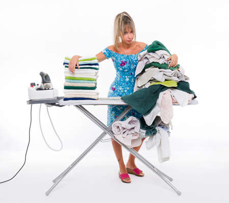 Woman with angry expression ironing on board many clothingの写真素材
