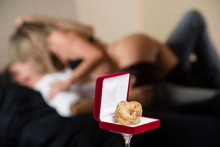 White truffle of Piedmont Italy, in red box for jewelry on the background undressed couple in loving effusionsの写真素材