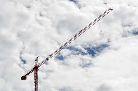 Construction crane in front of a blue sky full of white clouds