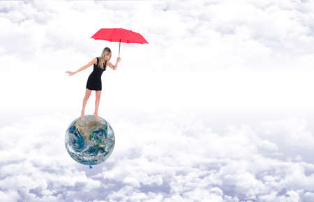 Barefoot girl on the planet earth, represented as a balloon, protects it with a red umbrella, while flying away on the white clouds in a blue skyの写真素材