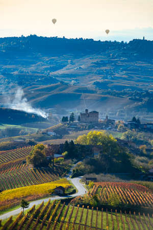 Grinzane Cavour, Italy - November 12, 2016: Road between the hills of Langa Piemonte Italy, at the bottom the castle of Grinzane cavour, in the sky two balloonsのeditorial素材