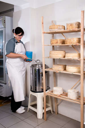 Cheesemaker pours the rennet with a ladle and a jug