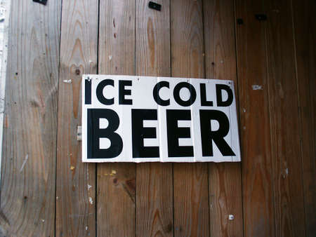 An "Ice Cold Beer" sign hanging on a wooden wall.の写真素材