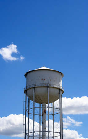 A white rusty watertower against a blue cloudy sky.の写真素材