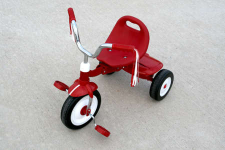 an empty red tricycle on a cement backgroundの写真素材
