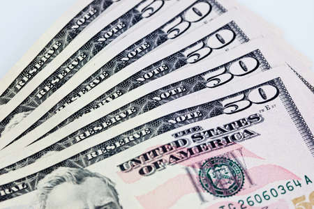 A stack of fifty 50 dollar bills fanned out on a white backgroundの写真素材