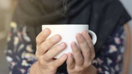 girl drinking and enjoying coffee during working in cafe. Close-up photo of Asian woman smelling and...