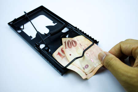 The hand is pulling the money out of the mousetrap.の写真素材
