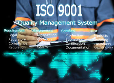 Man or auditor holding clipboard during an audit or assessment under the ISO 9001 quality management system concept and world map icon.の写真素材