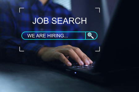Working man use laptop to find a job or job search and job finding work on dark background we are hiring concept.の写真素材