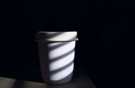 coffee cup with shadow beside the window on the black backgroundの写真素材