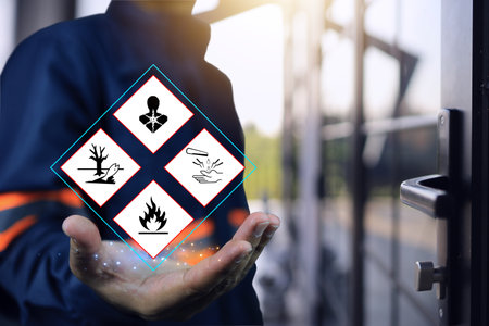 Warehouse personnel show warning signs of hazardous substances in hand, indicating preparedness in emergency situations and preparations to prevent potential dangers. MSDS and safety chemical concept.の写真素材