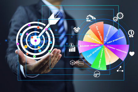 Setting business target goal with the business model canvas tool ensure accuracy goals in start up. Businessman holding dartboard and target mark point on board positioning business model on pie chartの写真素材
