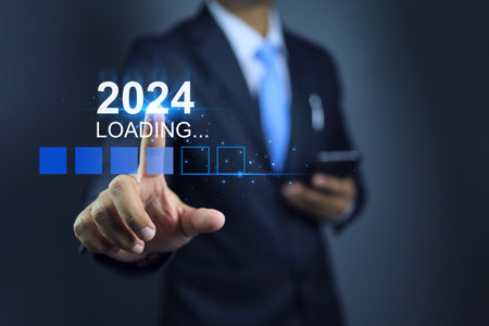 Businessman holding smart phone and touching on loading for new year 2024 to start the business planing and goal with action plan strategy for chalange revenue targetの写真素材