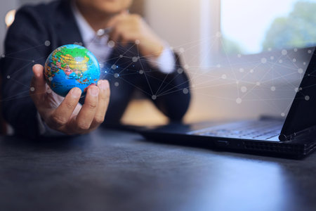 A businessman holds a globe in his hand, symbolizing borderless communication in international trade.の写真素材
