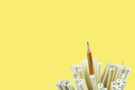 out standing concept with a sharp pencil stands out from the crowd on yellow background,...