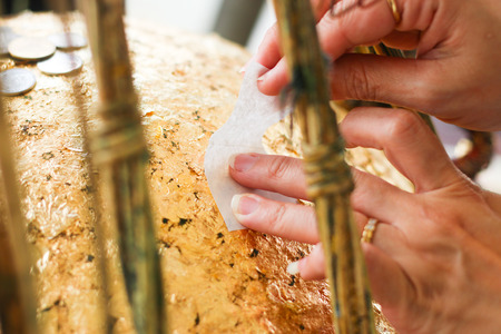 Hands are putting paper on the gold ball.の写真素材