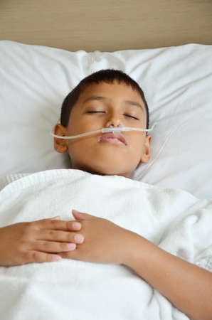 Sick boy sleeping with oxygen line on his nose の写真素材