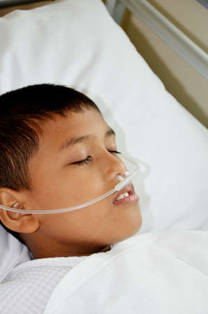 Sick boy sleeping with oxygen line on his nose の写真素材