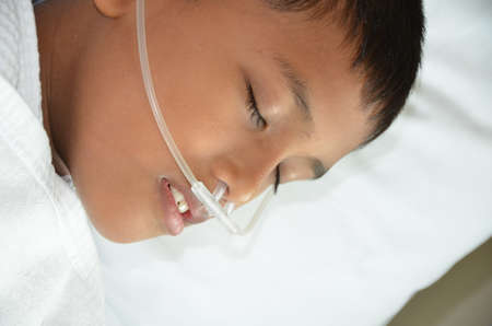 Sick boy sleeping with oxygen line on his nose 